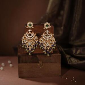 Indian gold-plated Chaandbali earrings featuring intricate Jadau Kundan work, pearls, and green and purple gemstone beads